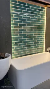 Backlit green subway tile wall behind a bathtub (2)